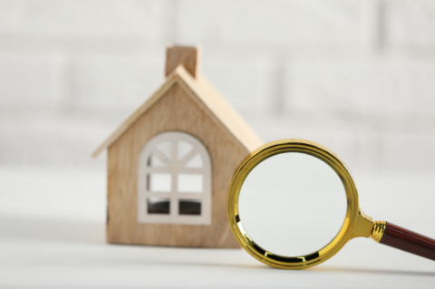 Toy house with a magnifying glass infront of it.